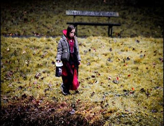 Child dressed gothic in a park next to a bench