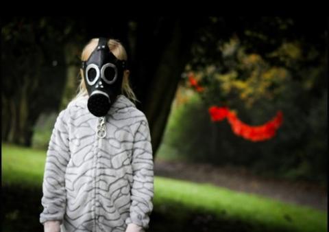 Child in a spooky gasmask in a park