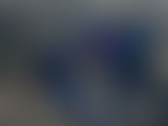 People hiking on a muddy trail through grassy moorland, wearing winter jackets. Overcast sky sets a calm, cool mood.