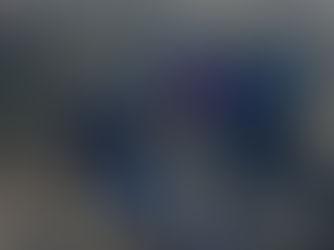 People hiking on a muddy trail through grassy moorland, wearing winter jackets. Overcast sky sets a calm, cool mood.