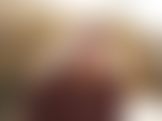 Smiling woman in a maroon hoodie labeled "ST. PAUL STRONG," outdoors by a river. Sunlight and trees create a warm, cheerful atmosphere.