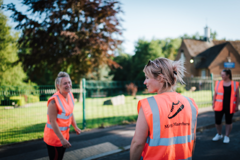 Women in high-visibility jackets are in a park