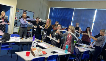 staff at a school are being physically active in a classroom