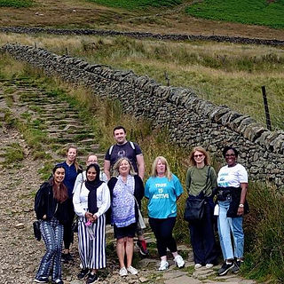 Group of walkers posing for the camera next to a wall in a green area