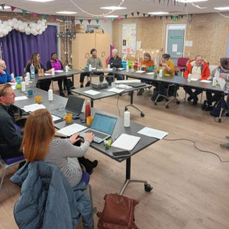 people around a room at a conference with laptops and notepads