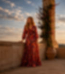 Woman in long patterned dress on a balcony at sunset