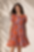 Woman in patterned orange dress for a b2b apparel sourcing agency.
