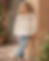 Girl in embroidered white top and blue jeans.