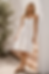 Woman leaning against a wall wearing a white tiered dress