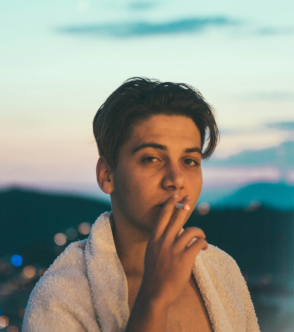 young man smoking cigarette in a bath robe outside
