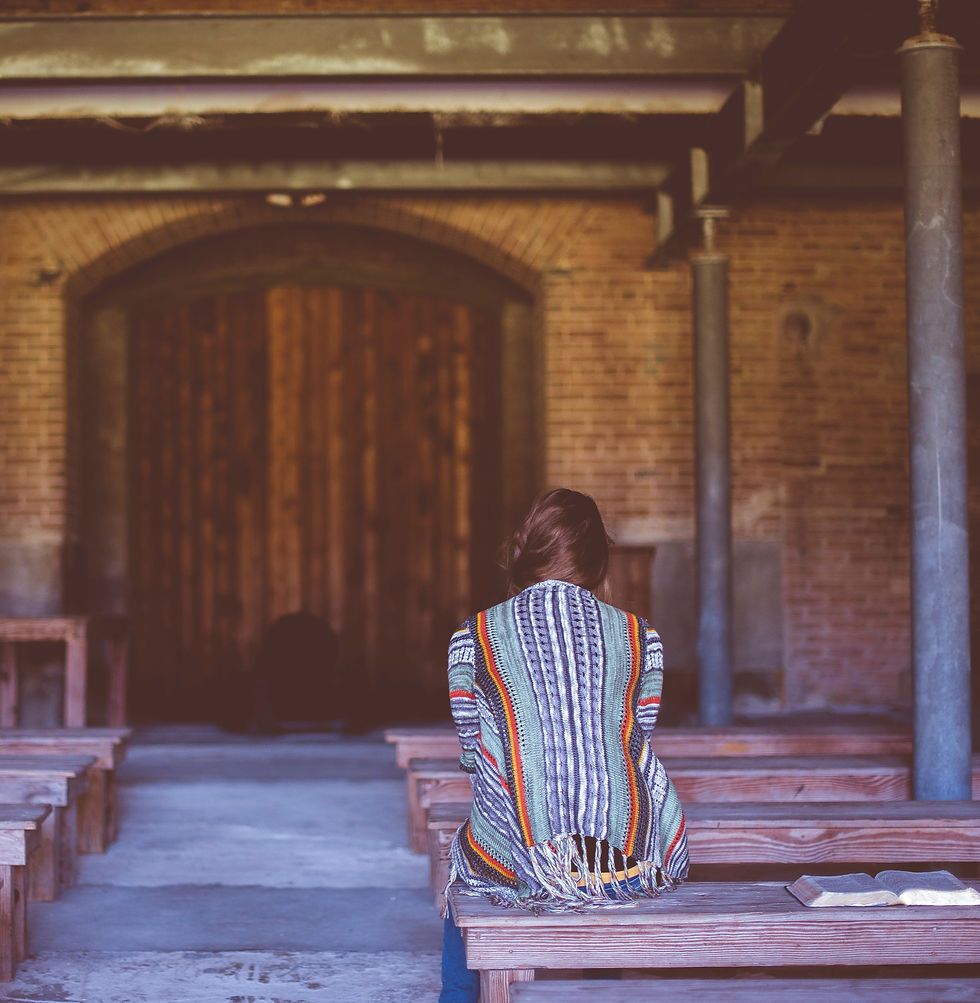 woman on bench in building with open Bible next to her