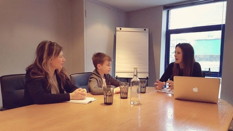 A child learns about etiquette sitting with his mother in a meeting room