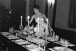 jacqueline kennedy onassis dressed elegantly lighting the candles on a dinner table