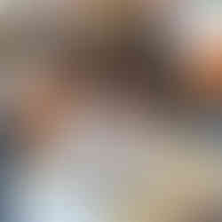 O elevă cu părul creț, concentrată, scriind la masa de lucru în sala de clasă.