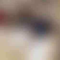 Un elev așezat la bancă, zâmbind spre cameră, având în față o foaie de examen și un pix.