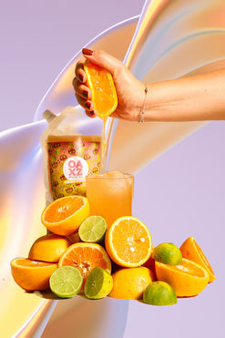 se muestra el punch sabor citrus , en una perfecta combinación de naranja con limón verde dando un. suculento sabor cítrico en mix con el mezcal experimentando u na explosión de sabor, en la parte gráfica se muestra una mano femenina exprimiendo una mitad de naranja sobre el vaso largo con la bebida preparada en las rocas con varias naranjas y limones cortados por mitad alrededor del vaso y el punch simulando una montaña con fondos muy claros color lila en forma de arcoíris 