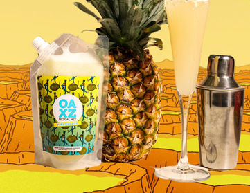 Punch presentation, Piña Colada flavor, best represented with a pineapple behind a Champagne-style glass and a shaker in a cartoonish yellow desert landscape.