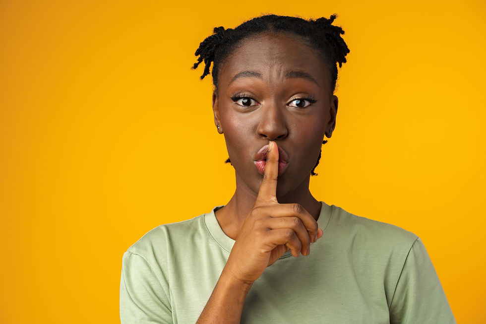 Young african american girl showing you shh sign in yellow studio.jpg