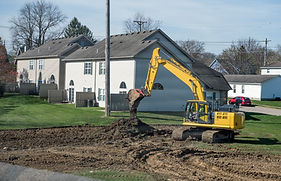 Excavator or backhoe dumping excavated soil into a pile at housing construction site in ea