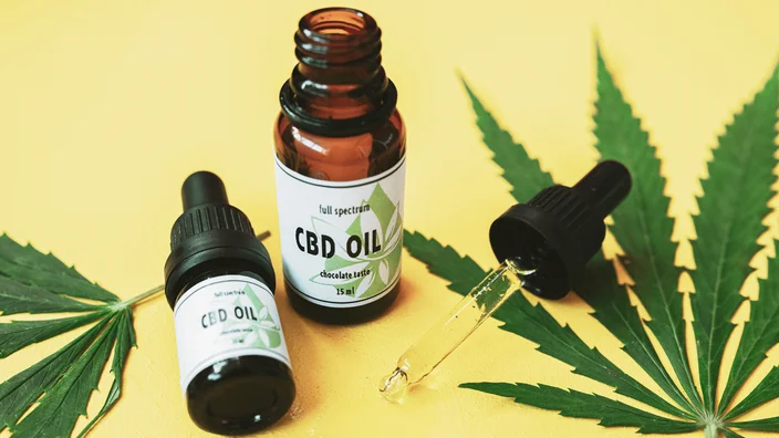 Full spectrum CBD oil bottles in a yellow background with cannabis leaves