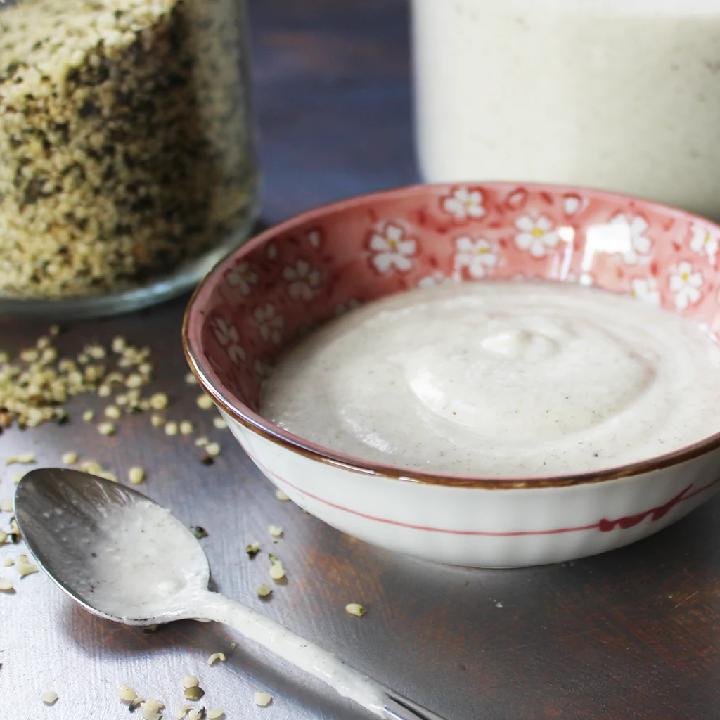 Hemp yogurt in a bowl with a jar full of hemp hearts in the background
