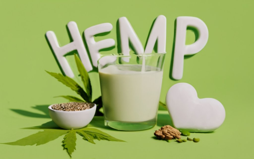 create an image of a Glass of hemp milk, with a bowl of hemp seeds, a bowl of hemp hearts, hemp leaves around in the background, with a title - "HEMP MILK" in the center. , typography, 3d render, conceptual art, illustration