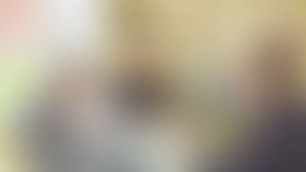 Three women enjoy tea and biscuits indoors, surrounded by vintage décor and colourful signs. They appear cheerful and engaged in conversation.