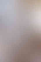 Rows of colorful eyeglass frames on display in a well-lit store. Visible brand logos include "BOSS" and "LAND ROVER". Neutral tones.