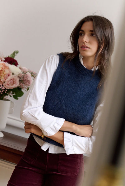 Vue de face du pull bleu marine à col rond côtelé, superposé à une blouse blanche