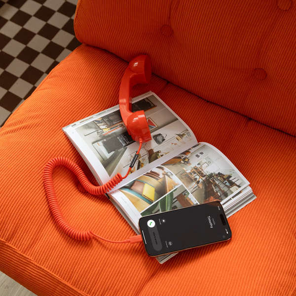 Miniature : Pop Phone Rouge Native Union posé sur un magazine et un fauteuil en velours orange, combiné branché à un smartphone.