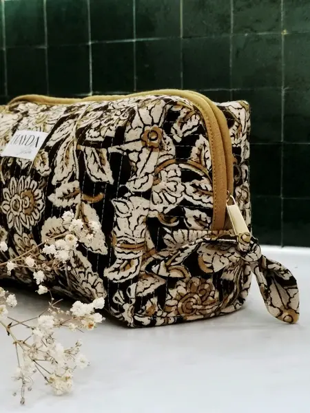 Miniature : Motif floral brun et écru de la trousse Pushkar Nayda Diaries avec détail du logo et flacon décoratif.