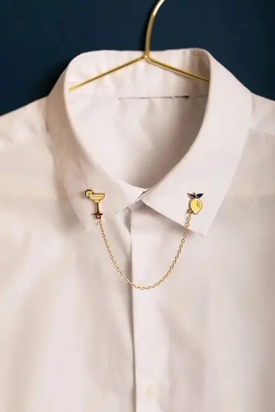 pin's chaîne margarita et citron en émail doré porté sur chemise blanche