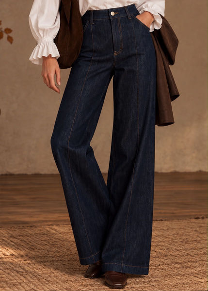 Jean femme large bleu foncé Ycoo, à taille haute et coutures devant, porté avec une blouse écrue et une veste brune.