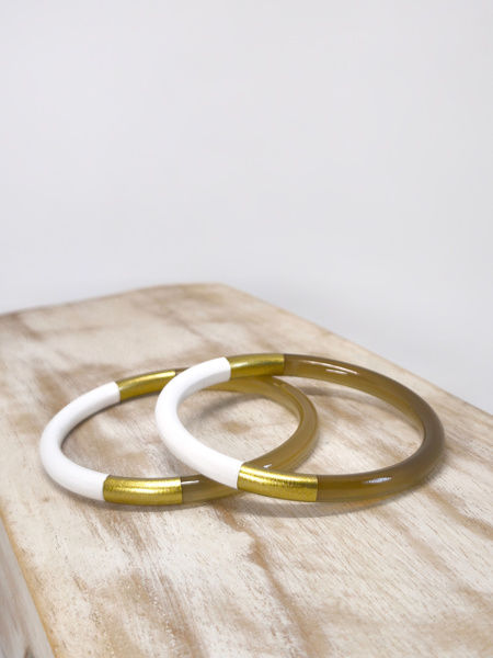 Deux joncs en corne naturelle, blanc et doré de 6 mm, présentés sur un support en bois.