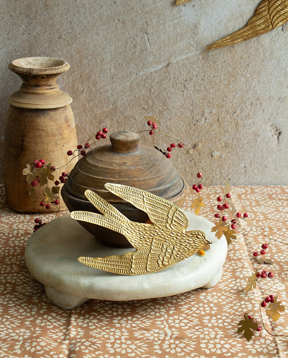 Hirondelle dorée en laiton posée devant des vases, avec un autre oiseau au mur