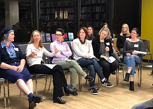 A group of women sitting in a row of chairs having a discussion.