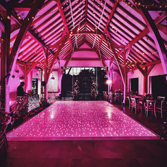 Pink uplighting in a barn with fairylighting and white starlit dancefloor.