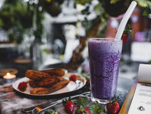 Un smoothie violet avec des churros et des fraises dans un restaurant en terrasse