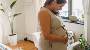 Une femme enceinte dans une chambre lumineuse qui sourit