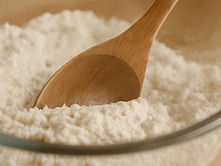 A bowl of flour with a wooden spoon