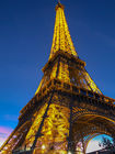 Eiffel Tower illuminated at night against a dark blue sky.