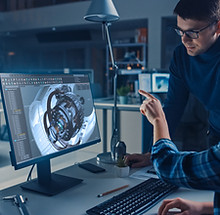 Engineer Working on Desktop Computer, Screen Showing CAD Software with Engine 3D Model, He