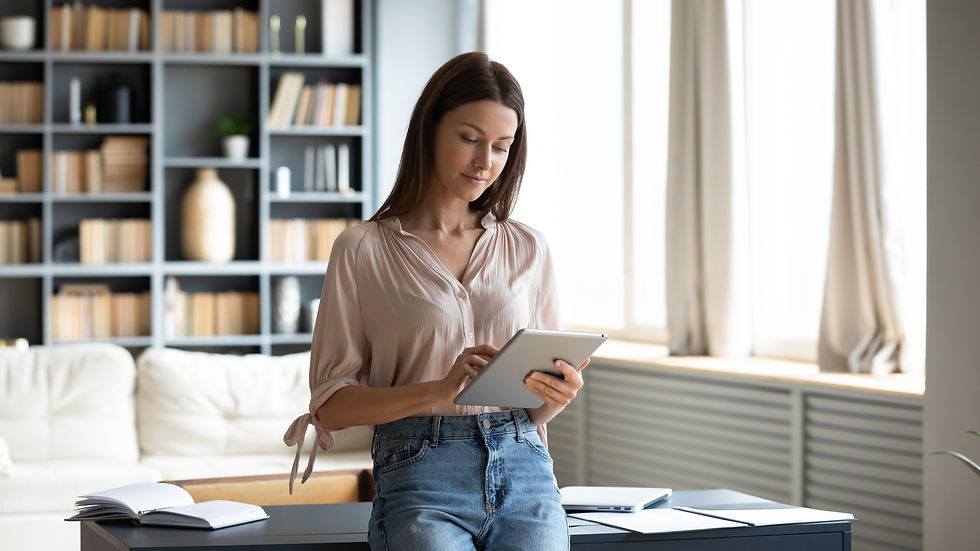 Beautiful young woman using computer tablet, standing in modern living room at home, spend