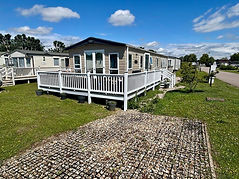Front view of holiday home , beige with dark trim and double patio doors