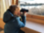 Girl looking out of bird hide with binoculars