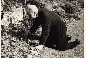 Black and White image of E A Bowles kneeling down weeding in the Rock Garden