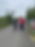 A walk leader walking alongside one of the walk participants who is using walking poles