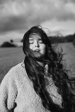 Black and white portrait of a woman with wind blown hair in a textured coat