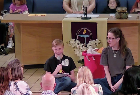 youth sitting on pulpit leading service with adults sitting on quilt in Time for All Ages