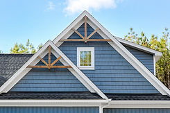 Suburban Blue House Gable Roof With Wooden Trusses And A Window Under A Clear Sky.jpg